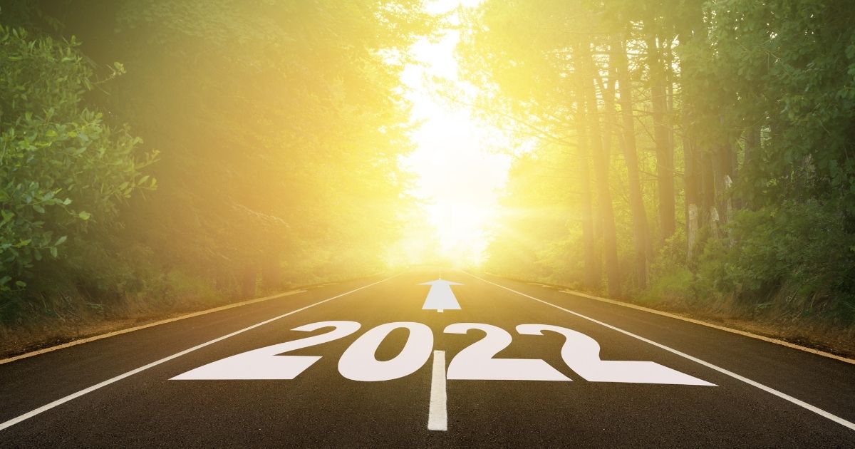 2022 painted on to a roadway in a forest with sunrise in the distance, representing 5 reasons to use a recruiter in 2022